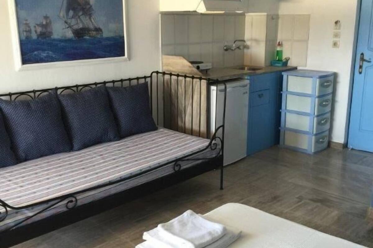 Ein gemütlicher Raum mit Bett, einer kleinen Couch, einer Küchenzeile und einem Badezimmer.