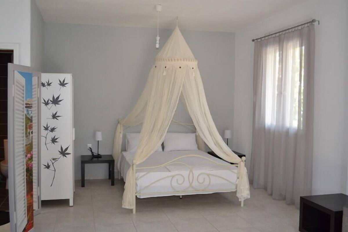 Ein Schlafzimmer mit Baldachinbett, Nachttisch, Kleiderschrank und Beistelltisch.