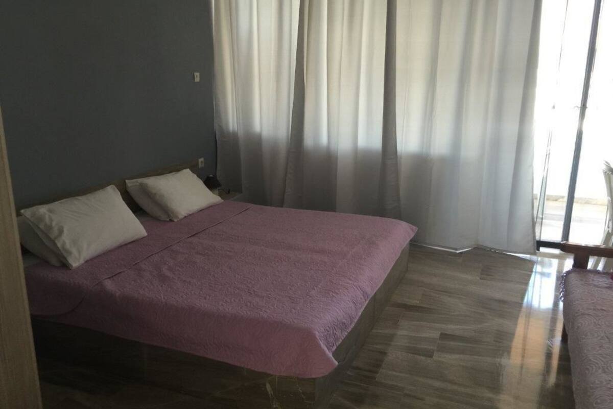 Ein Schlafzimmer mit einem Bett, zwei Kissen, Holzboden und einem Vorhangfenster.
