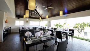 A restaurant with multiple tables set for dining, ceiling fans, and pendant lights. - Temple Tree Hotel (Bengaluru)