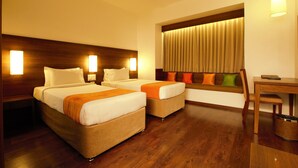 A hotel room with two beds, a desk, and a window with curtains. - Temple Tree Hotel (Bengaluru)