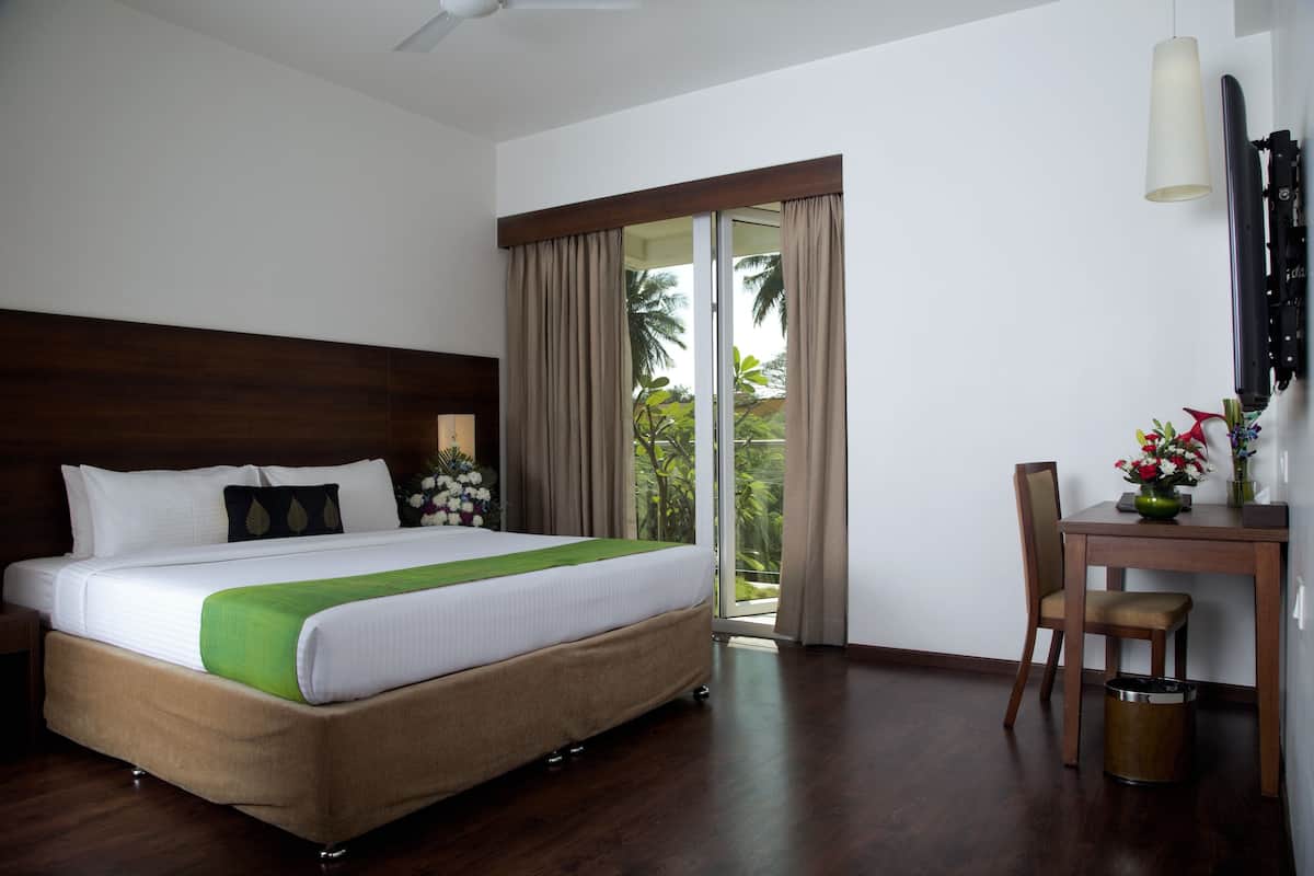 A hotel room with a bed, a desk, a chair, and a view of the outdoors.