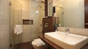 A modern bathroom with a glass shower enclosure, a white sink, and a marble countertop.