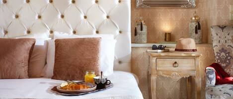 A hotel room with a tufted headboard, a bedside table with a lamp, a chair, and a mirror.