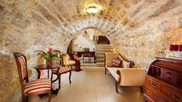 A stone-walled room with a dining table, chairs, and a sofa.