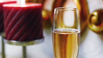 A glass of champagne with a lit candle in the background.