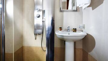 Une salle de bain avec une douche, un lavabo et un miroir.