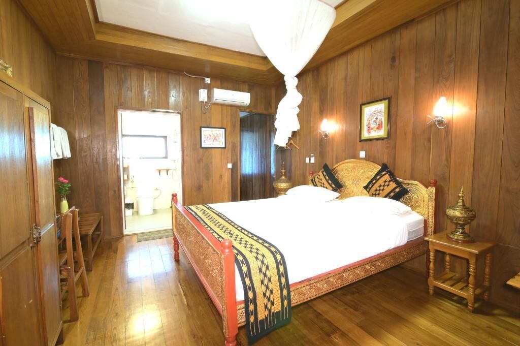 A wooden-paneled room with a large bed, a bedside table, and a hanging light fixture.