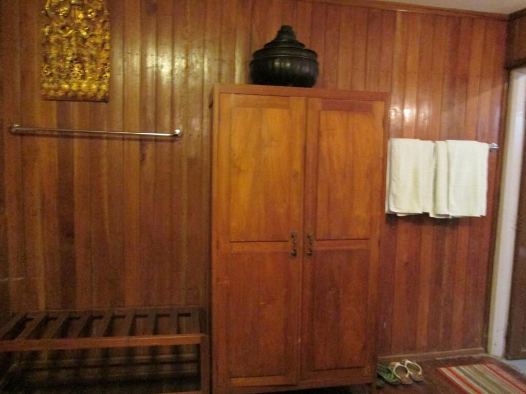 A wooden-paneled room with a wardrobe, a towel rack, and a pair of shoes on the floor.