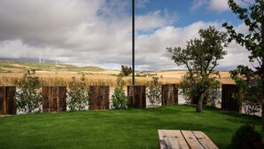 Et græsplænet område udendørs med et træhegn, et højt pæle og et picnicbord.