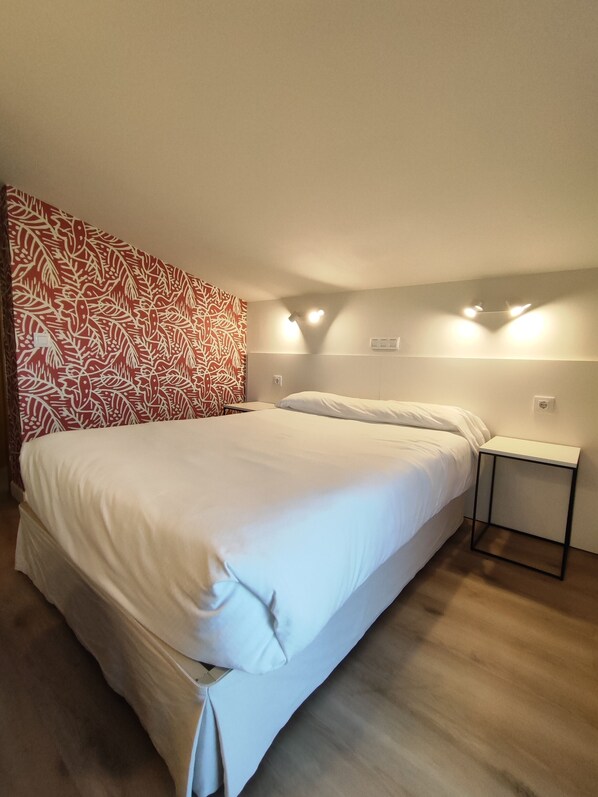 A bedroom with a bed, a bedside table, and a patterned wall.