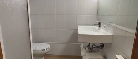 Un baño pequeño con inodoro, lavamanos y zona de ducha.