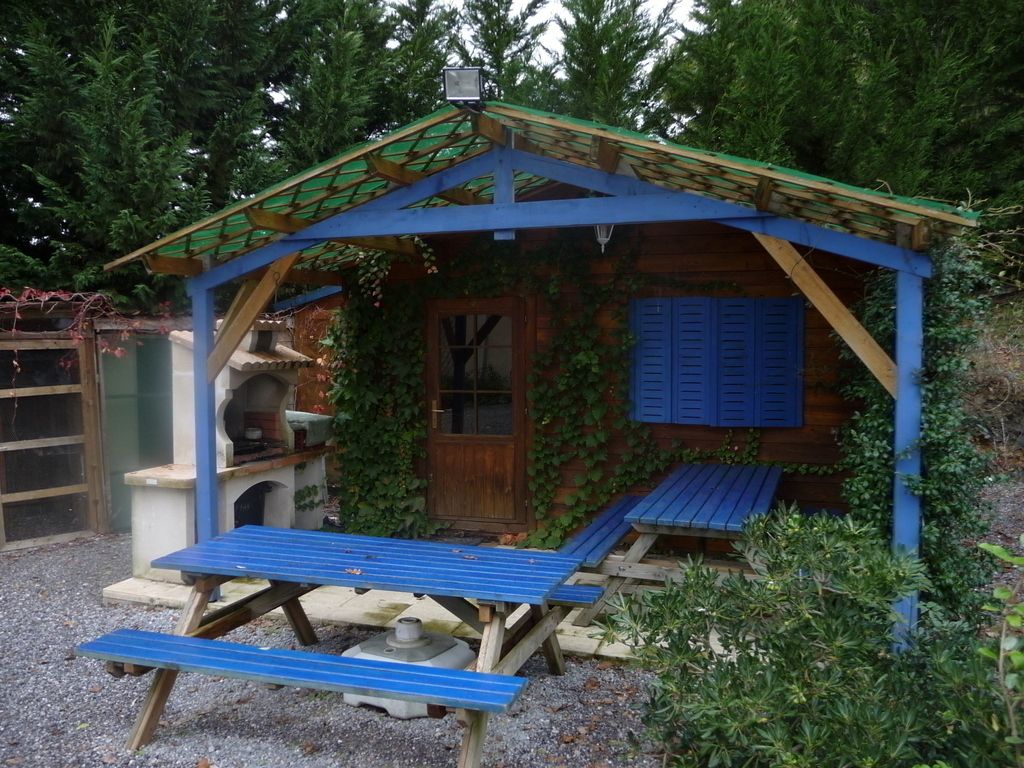 A small wooden cabin with a green roof, a wooden door, and a blue bench outside.