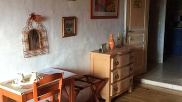 Una habitación acogedora con pisos de madera, una mesa de madera con sillas, un aparador y obras de arte colgadas en la pared.