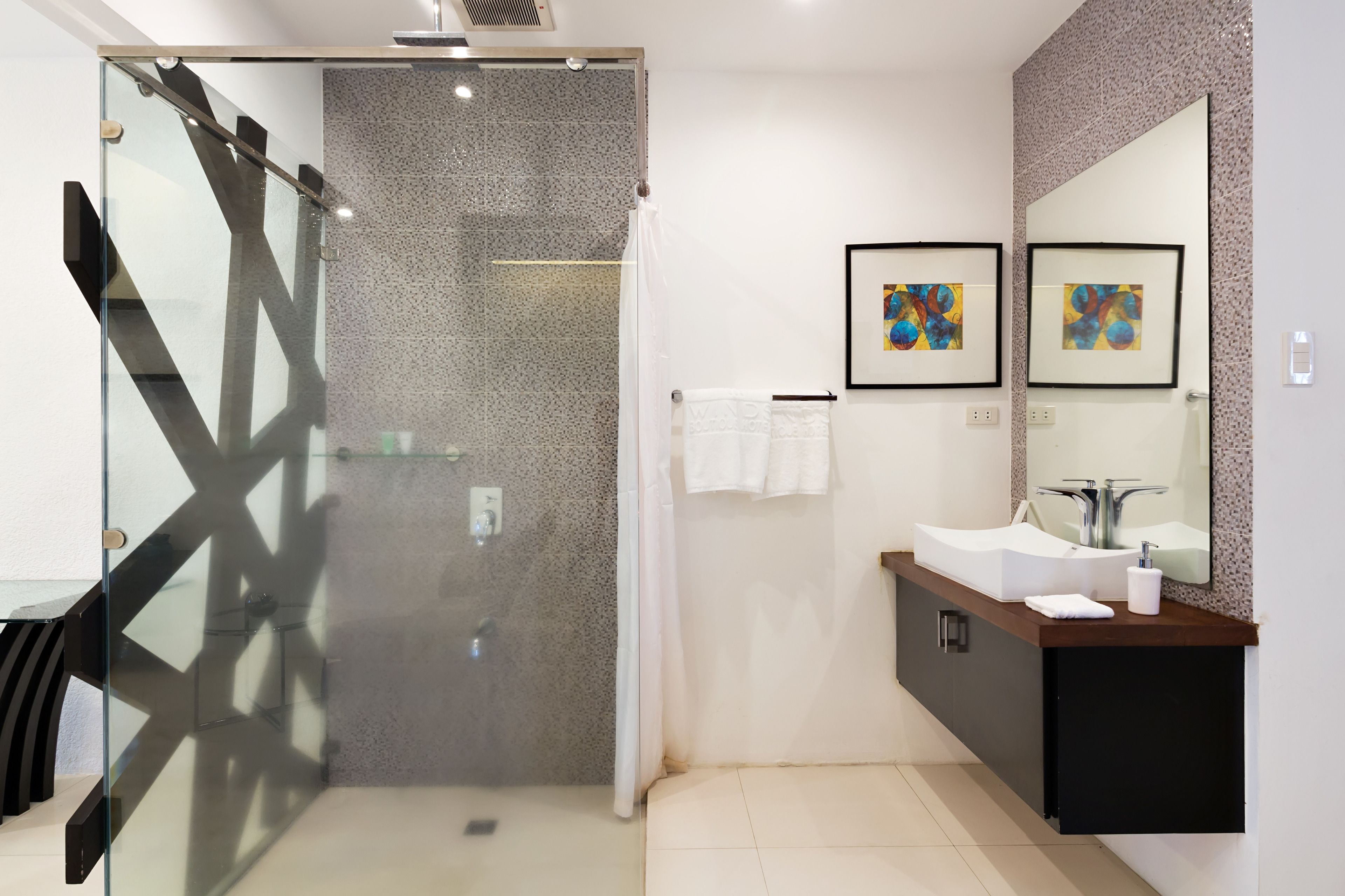 A modern bathroom with a glass shower enclosure, a large mirror, and a white sink.