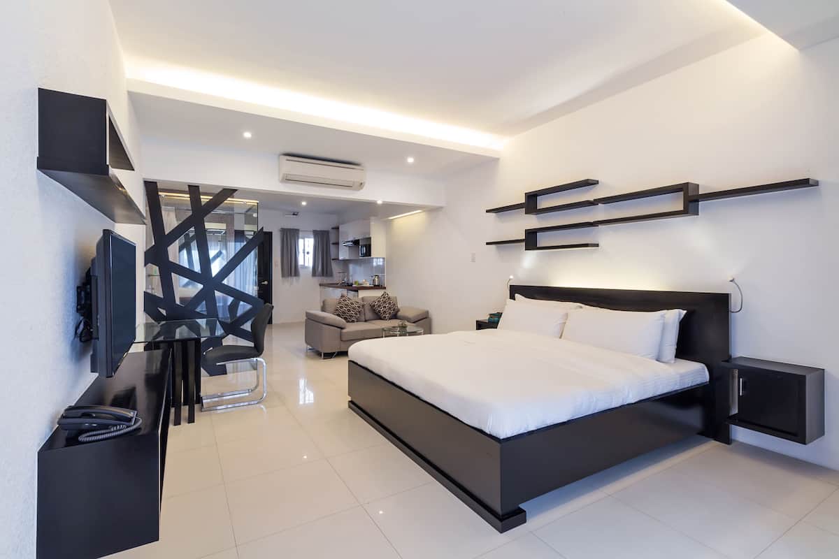 Une chambre moderne avec un grand lit, des tables de chevet, une télévision et un bureau avec un téléphone.