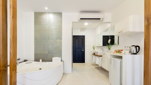 A modern bathroom with a large bathtub, a shower, a sink, and a toilet. There is a mirror above the sink and a door leading to another room. - Winds Boutique Hotel (Angeles City)