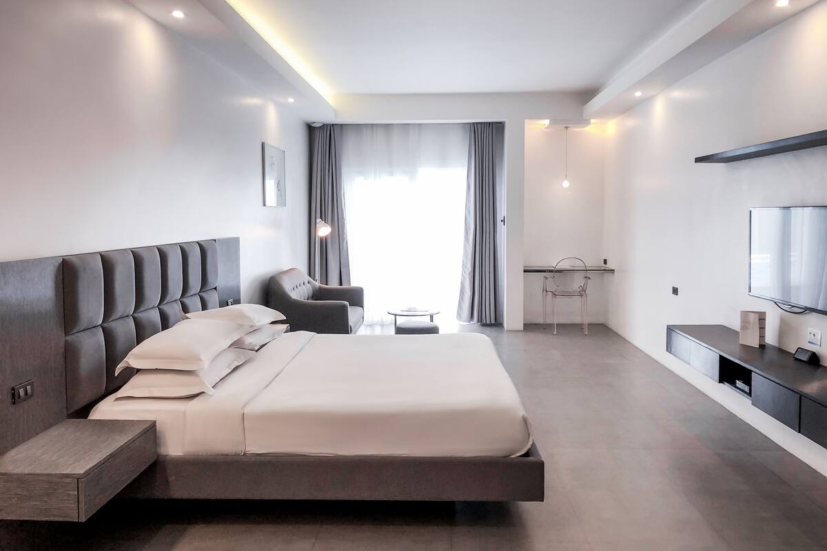 Une chambre d’hôtel moderne équipée d’un grand lit, d’un bureau, d’une chaise et d’un téléviseur.