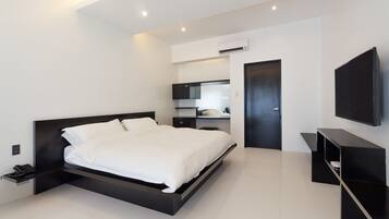 A modern bedroom with a large bed, built-in shelving, a flat-screen TV, and an air conditioning unit.