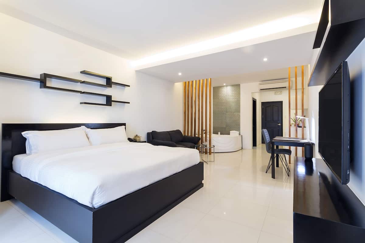 Une chambre moderne avec un grand lit, une télévision et un coin salon comprenant une table et des chaises.