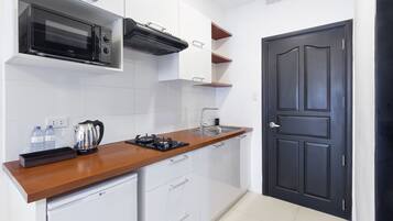 Cocina compacta con microondas, hervidor y lavabo.