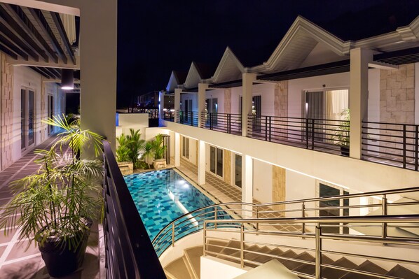 A multi-level hotel with a swimming pool, outdoor lighting, and a staircase.
