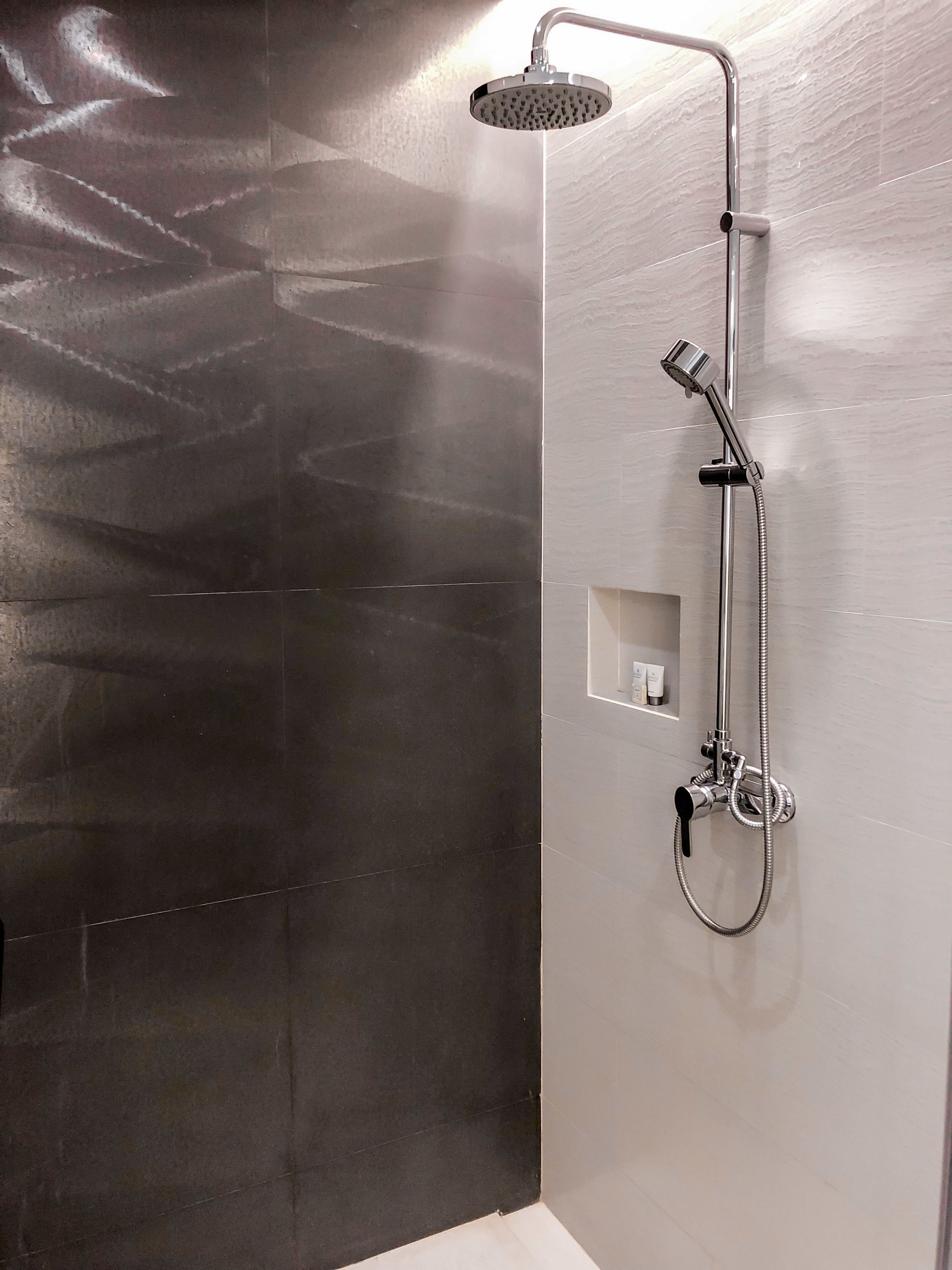 Una ducha moderna con cabezal de ducha manual y grifo empotrado en la pared.