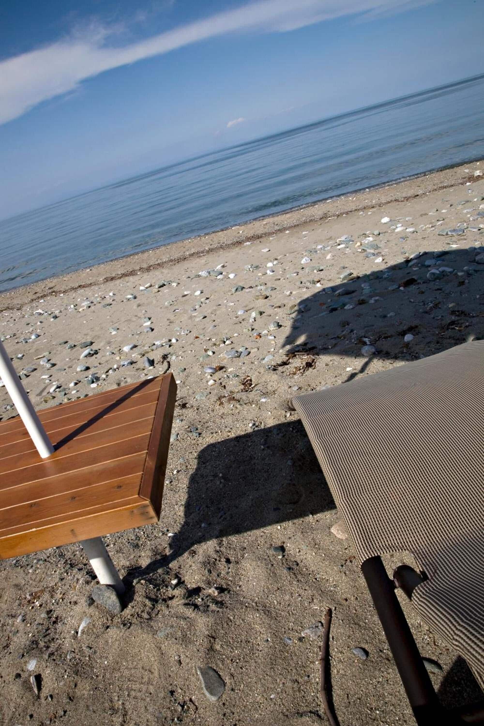 Una playa con una terraza de madera y una silla de metal.