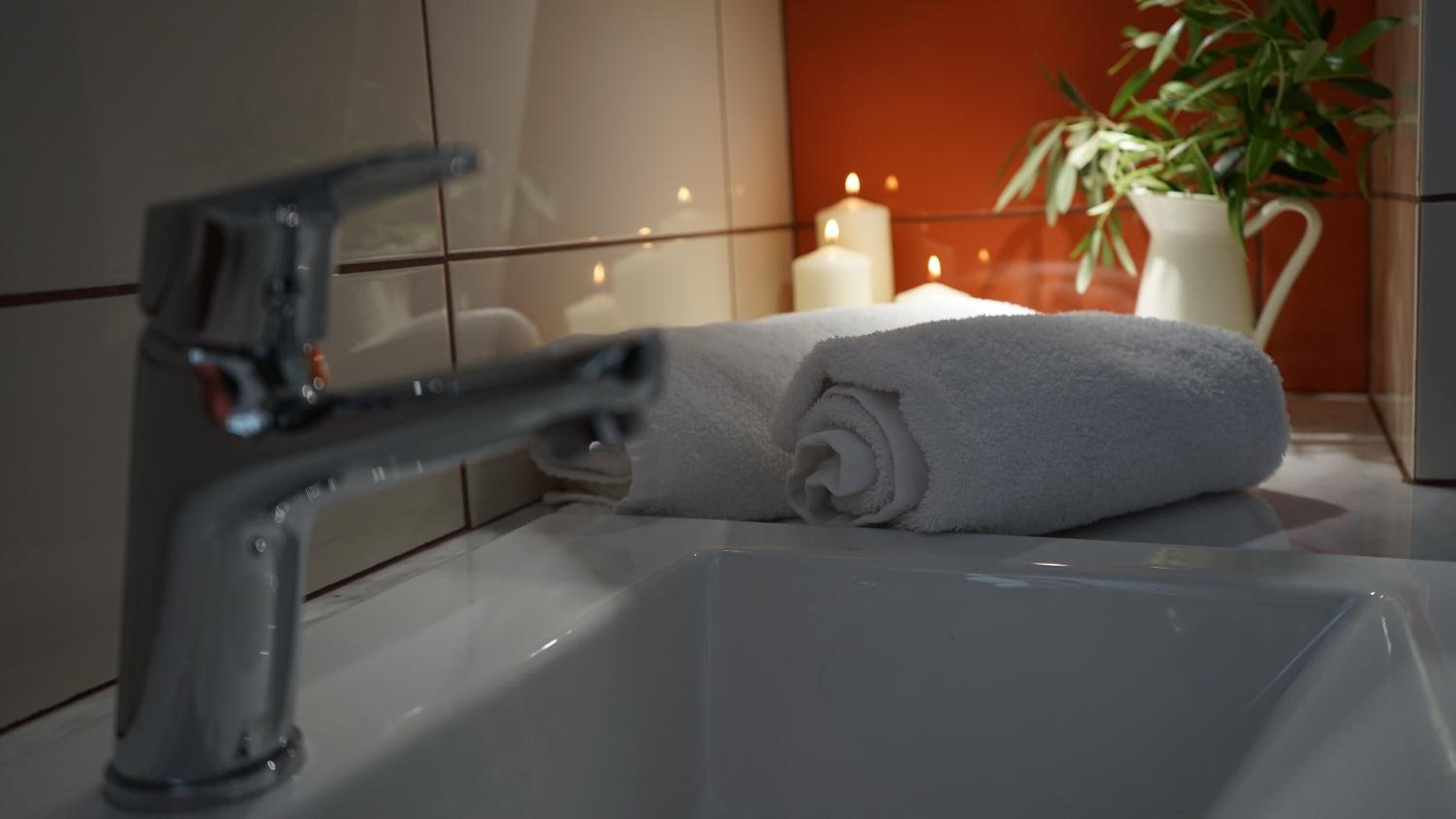 Un baño con un lavamanos moderno, una toalla y velas.