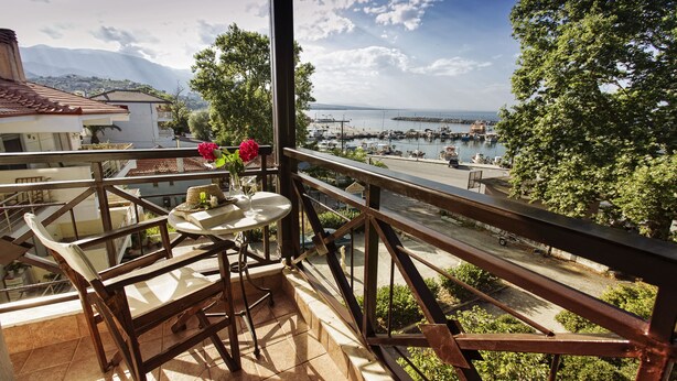 A balcony with a table and chairs, overlooking a marina and a mountainous landscape. - Hotel Morfeas (Dio-Olympos)