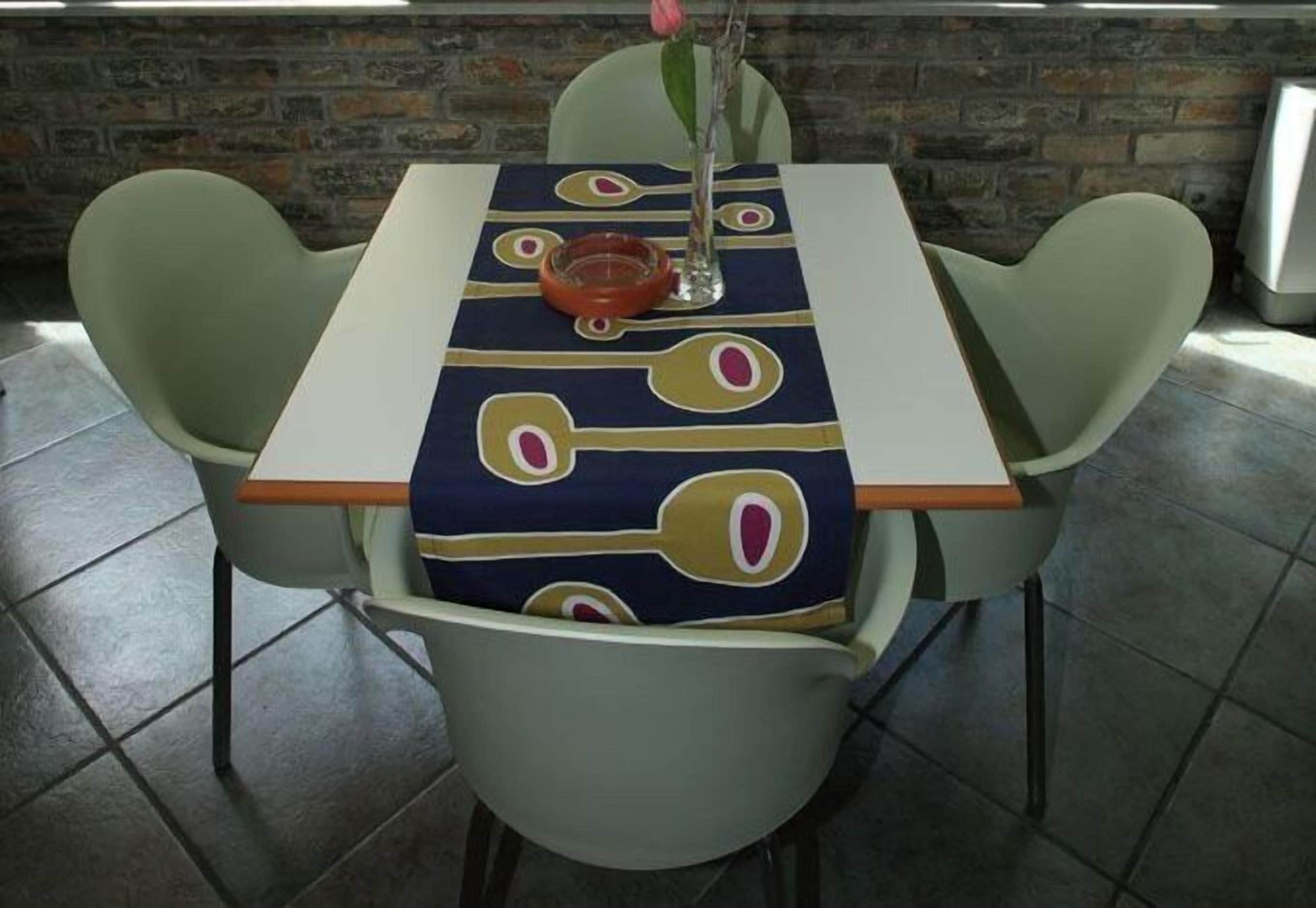 Una mesa de comedor con mantel estampado, rodeada por cuatro sillas.