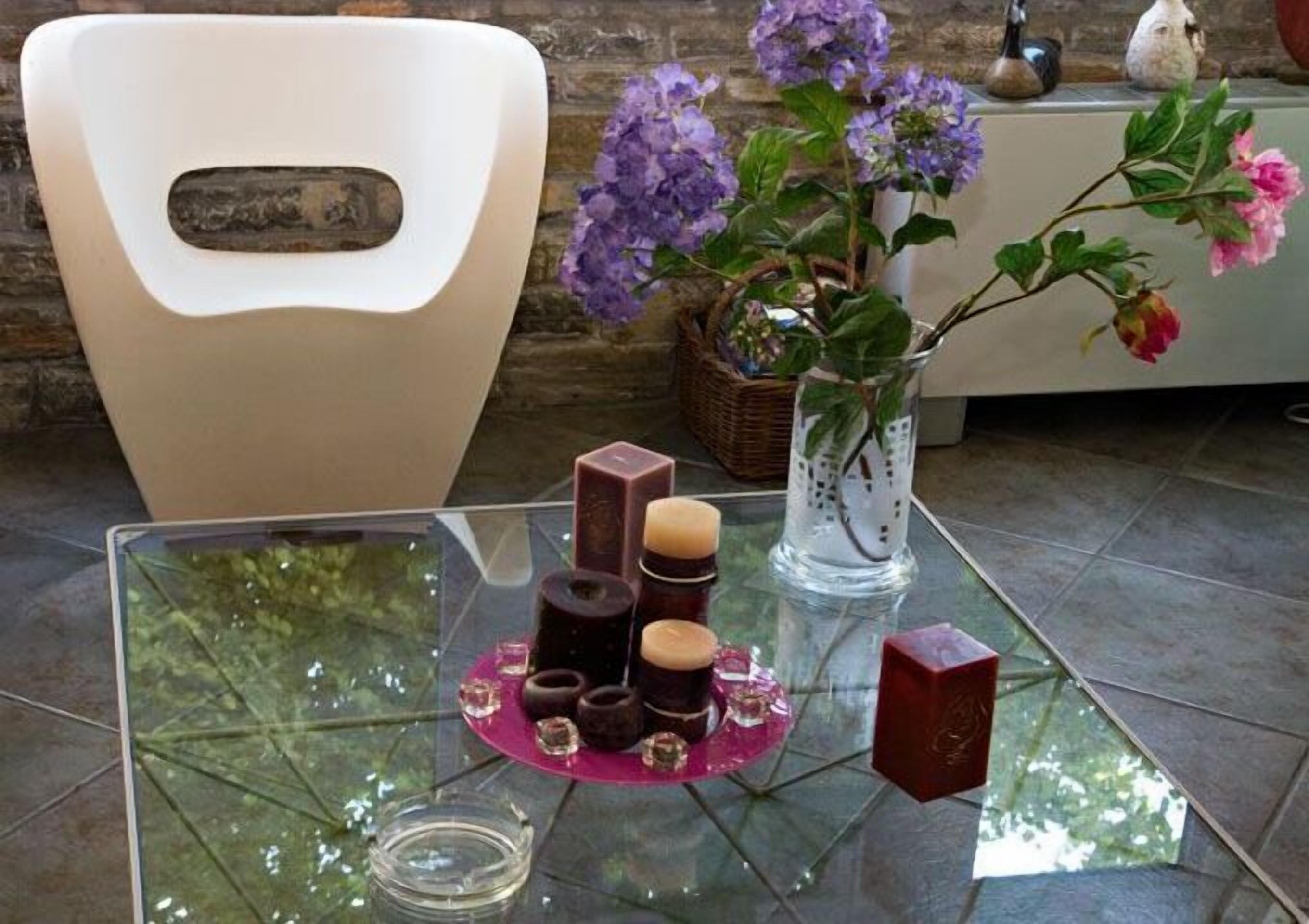 A glass table with a decorative arrangement of candles and a vase of flowers.