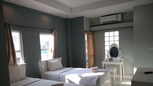A hotel room with two single beds, a white dresser, a mirror, and an air conditioning unit. - The Battery Park Midtown Boutique (Chiang Mai)