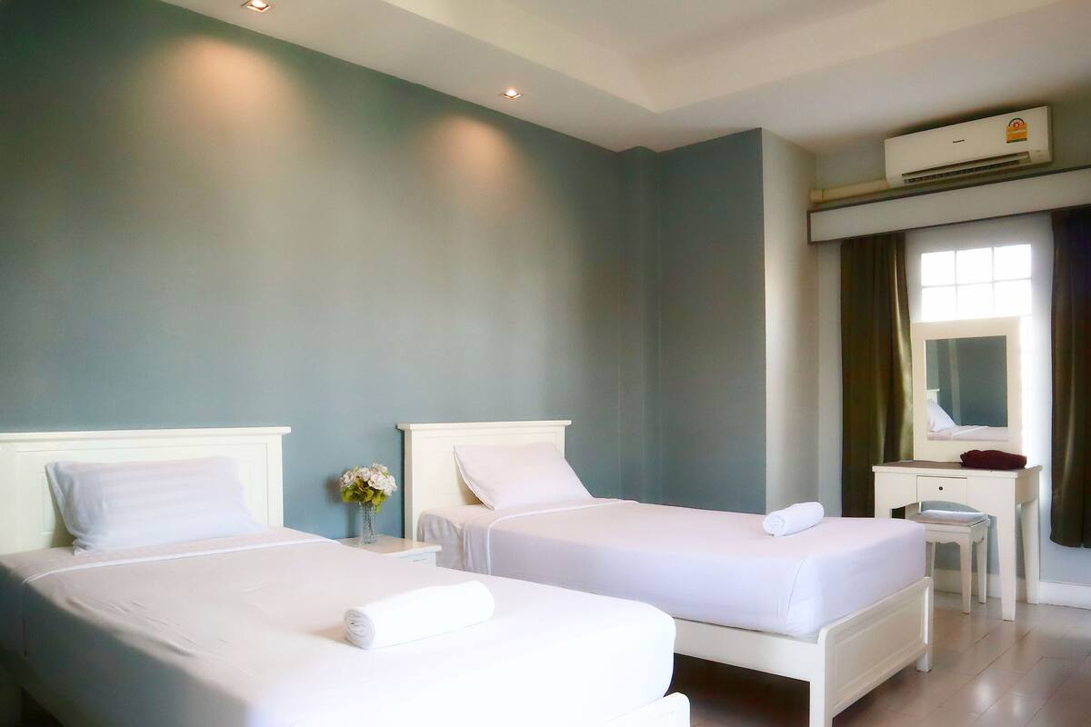 A hotel room with two beds, a desk, and a mirror.