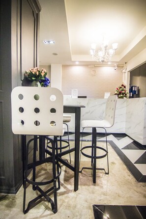 Una cucina moderna con un piano di lavoro in marmo, due sgabelli da bar bianchi e un lampadario.