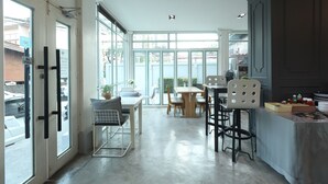 A spacious kitchen with large windows, a dining area, and a bar area. - The Battery Park Midtown Boutique (Chiang Mai)
