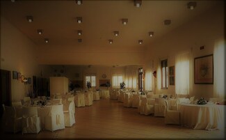 A large banquet hall with multiple round tables covered with white tablecloths and chairs.