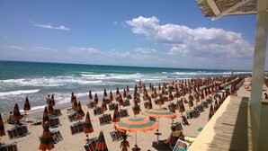 A beach with rows of sun loungers and umbrellas, a clear sky, and the ocean in the background. - Lido Impero (Massafra)