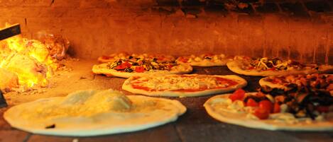 A brick oven with pizzas being cooked.