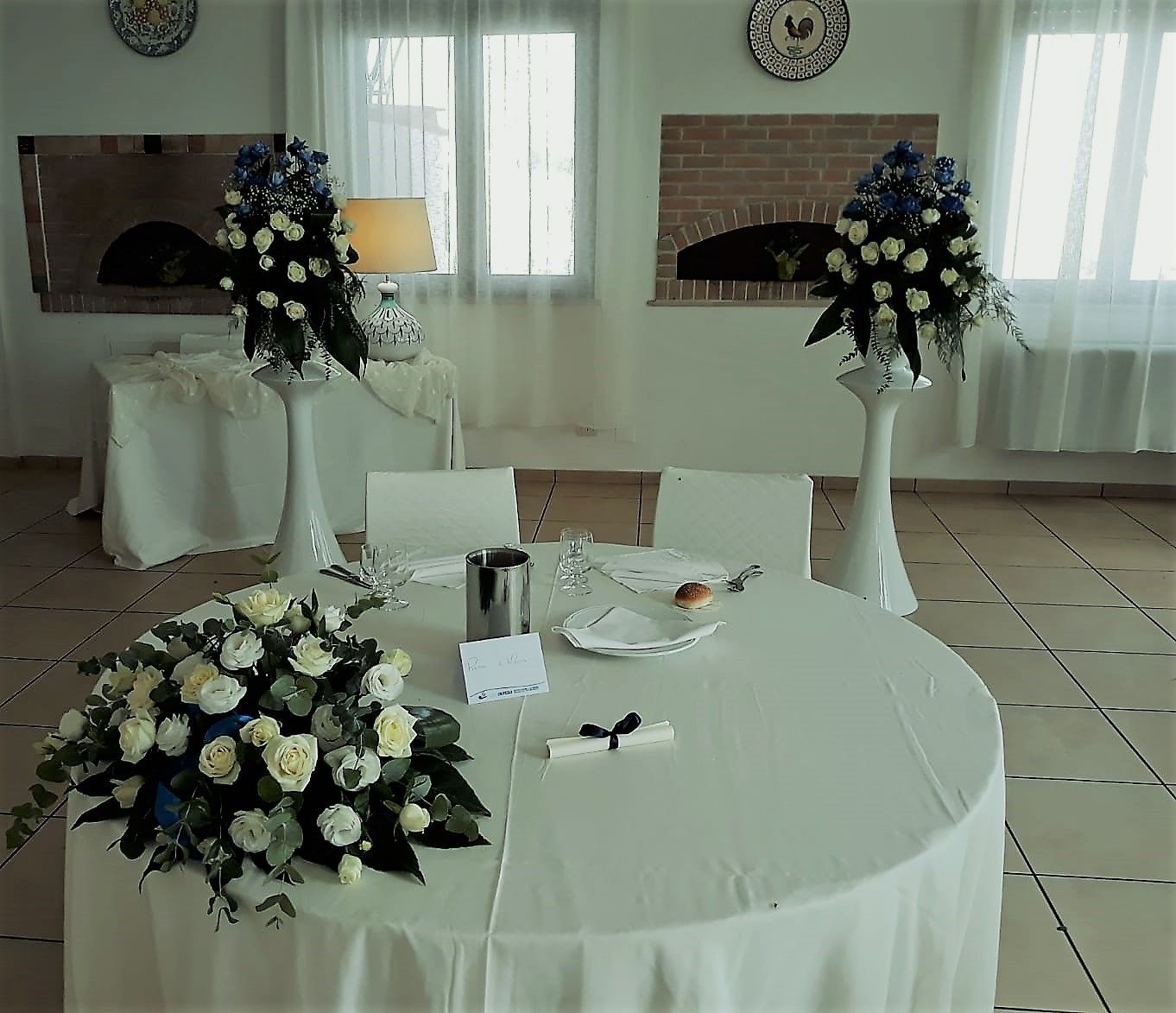 Un comedor con mesas redondas, manteles blancos y centros de mesa florales.