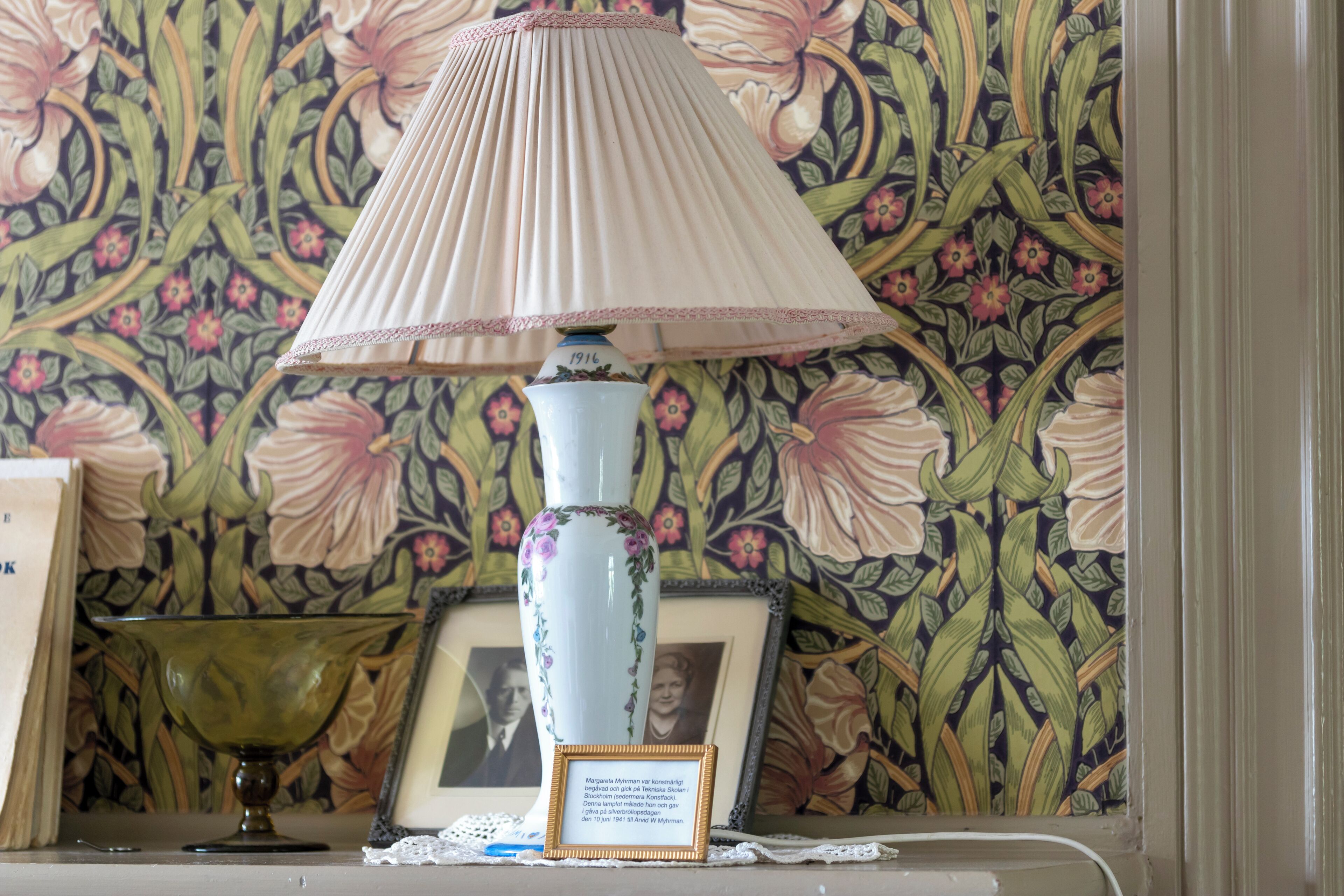 Una mesa con una lámpara, una fotografía enmarco y un cuenco decorativo.