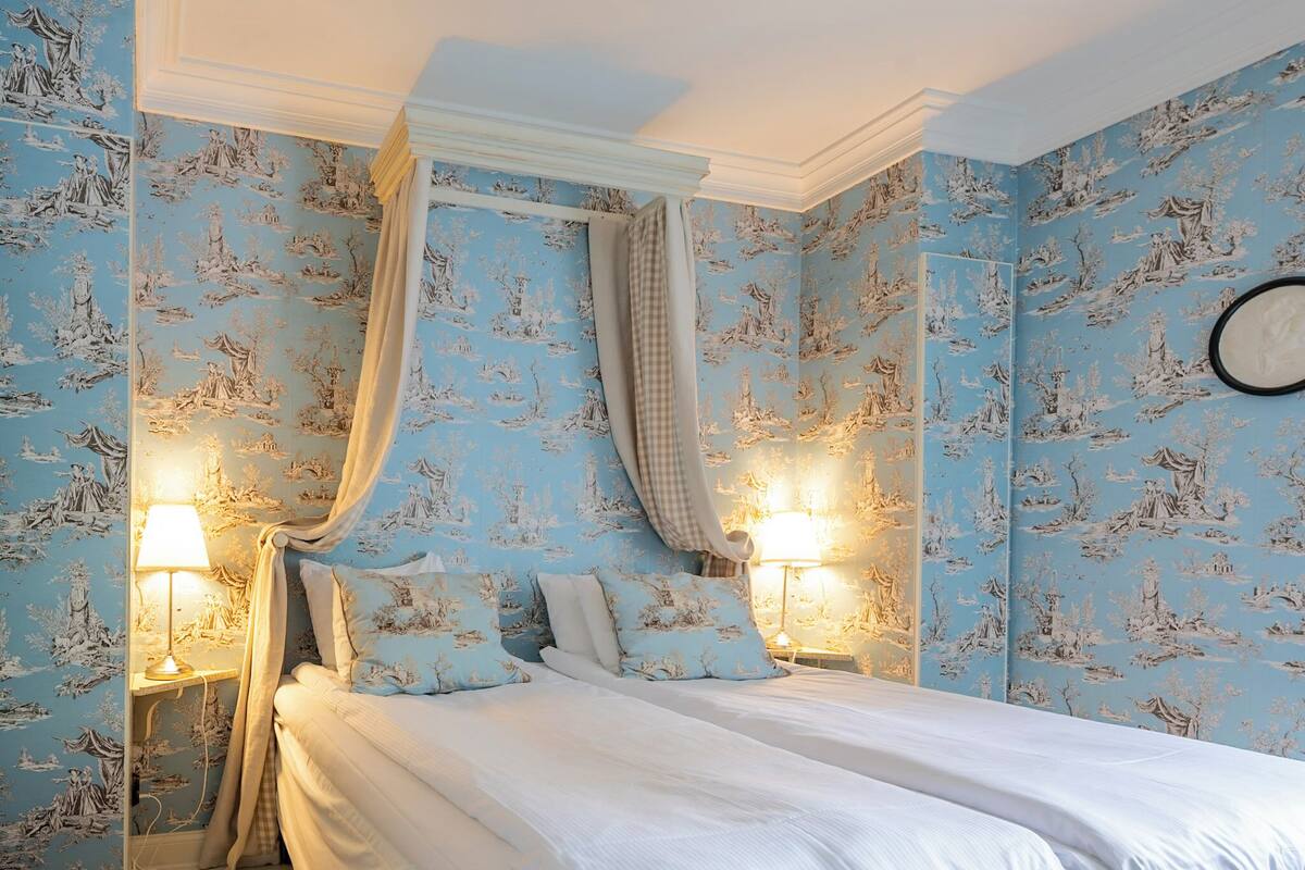 A bedroom with a large bed, two bedside lamps, and a wall clock.