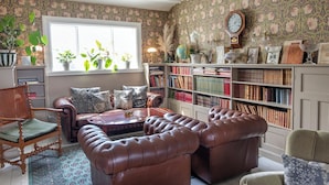 Un salon chaleureux avec des canapés en cuir, une table basse et une bibliothèque remplie de livres.