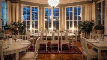 Een stijlvolle eetzaal met een grote ronde tafel, witte stoelen en een kroonluchter.