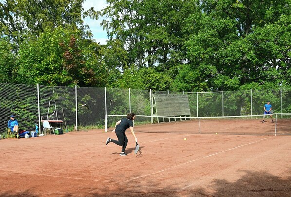 A tennis court with a net, surrounded by a fence and trees. - Villa Gransholm (Gemla)