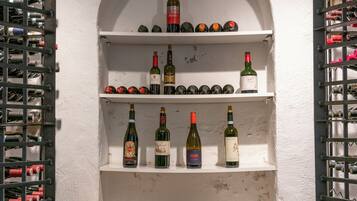 A wine cellar with shelves of wine bottles and boxes labeled 'DUNE' and 'Mestremilio'.