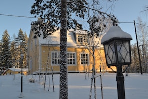 Una casa cubierta de nieve, con una ventana visible y un farol en primer plano.