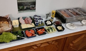 A buffet with various food items including bread, cheese, meats, and salads.
