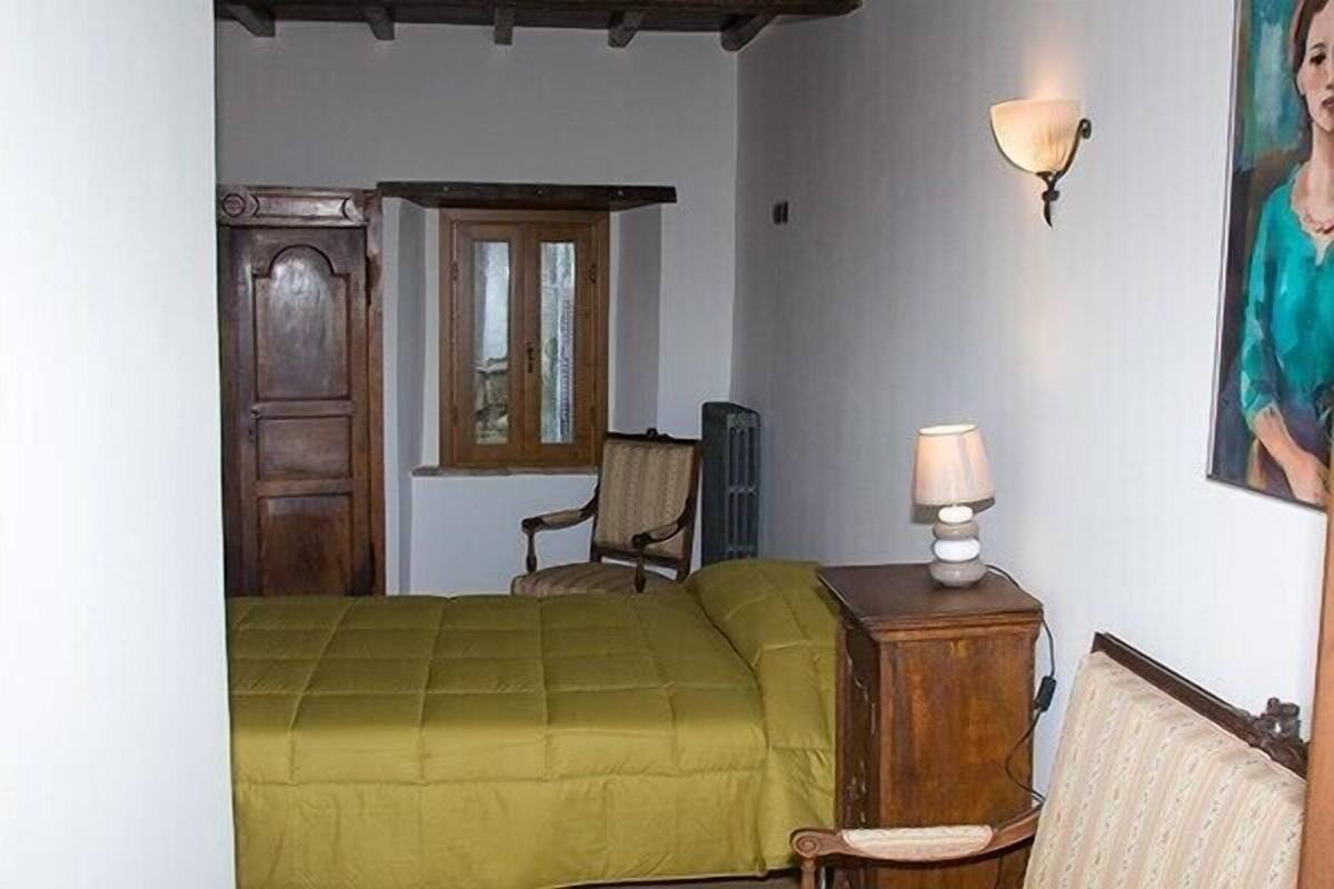 Een kamer met een bed, een stoel, een lamp en een schilderij aan de muur.