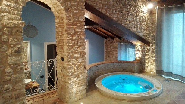 A stone-walled room with a hot tub, a wooden ceiling, and a view through an archway. - Residenza d'epoca & Spa Il Cerchio di Lullo (Fumone)